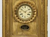 une image représentant une horloge dans un cadre doré, dont le cadran comporte des chiffres romains
