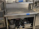 une cuisine avec un plan de travail en inox sur lequel sont posés tout un tas de casseroles et de poêles