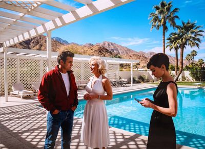 deux hommes et une femme debout près d'une piscine, un téléphone portable à la main