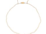 un collier de perles blanches avec un fermoir en or sur fond blanc