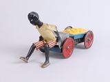 toy figurine of a man sitting on a cart with a basket of fruit