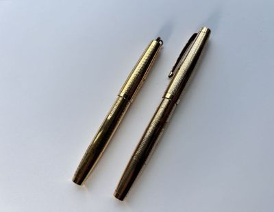 deux stylos sont posés l'un à côté de l'autre sur une surface blanche