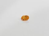 an orange sapphire stone on a white surface