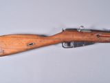 un vieux fusil avec un canon en bois sur une surface blanche