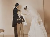 a man and a woman standing next to a little boy in a wedding dress