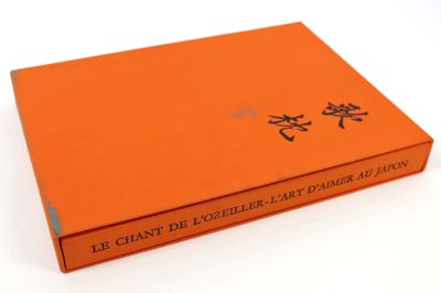 un livre orange portant des caractères chinois, posé sur une surface blanche