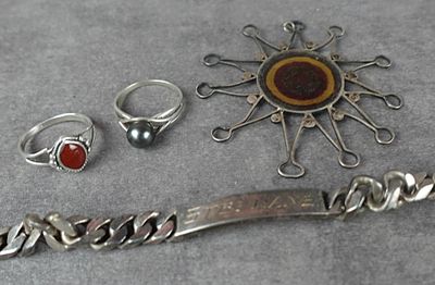 un bracelet en argent, une bague, un bracelet et d'autres bijoux posés sur une table
