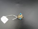 une bague en or sertie de pierres bleues et ornée d'une plaque, sur un fond noir