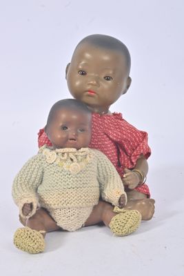 two dolls sitting next to each other on a white surface