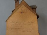 a cardboard house hanging on the wall next to a bed