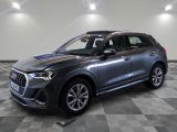 un SUV Audi gris garé sur un sol à damier dans un showroom