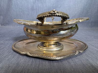 une assiette en argent antique sur laquelle est posé un bol