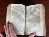 someone is reading a book on a wooden table with their hands on it