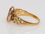a gold ring with an oval stone surrounded by filigree filigree