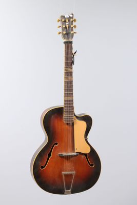 an old mandolin guitar sitting on a stand against a white background