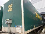 un gros camion vert garé devant un immeuble
