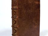 an old brown book with gold trim sitting on a white surface