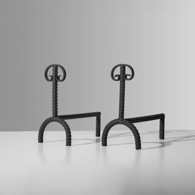 une paire de bougeoirs en fer noir posés sur une surface blanche