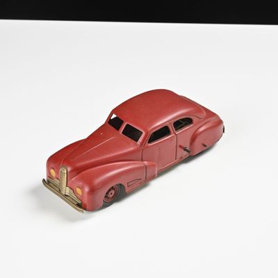 une petite voiture rouge posée sur une surface blanche