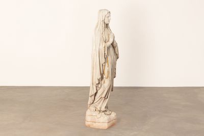 une statue représentant une femme portant un voile sur la tête, dans une pièce blanche