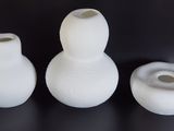 three white vases sitting on a table with a black background