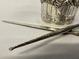 a silver cup with a spoon and a pair of scissors next to it