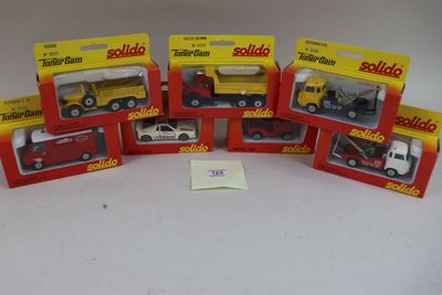 six camions miniatures assortis, emballés dans leurs boîtes, posés sur une surface blanche