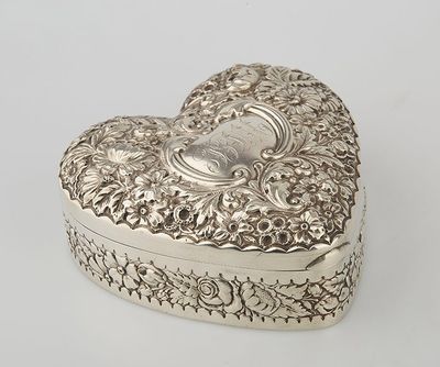 a silver heart shaped box on a white surface