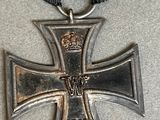 an old iron cross with a ribbon and a crown on it