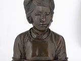 a bronze statue of a woman sitting on a table