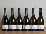six bottles of wine are lined up on a wooden table