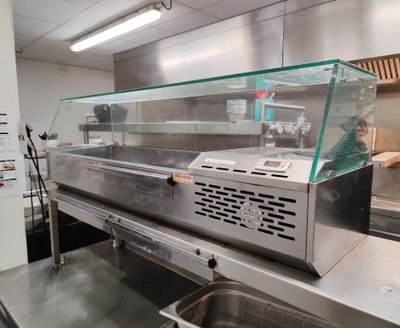 plan de travail en acier inoxydable dans une cuisine professionnelle équipée d'une vitrine en verre