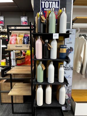 une étagère noire sur laquelle sont disposées de nombreuses bouteilles dans un magasin