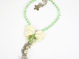 green beaded necklace with white flowers and a silver butterfly charm