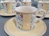 three cups and saucers on a table with a teapot