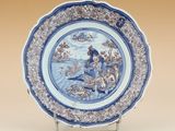 une image représentant une assiette bleue et blanche sur laquelle figure une femme dans un bateau