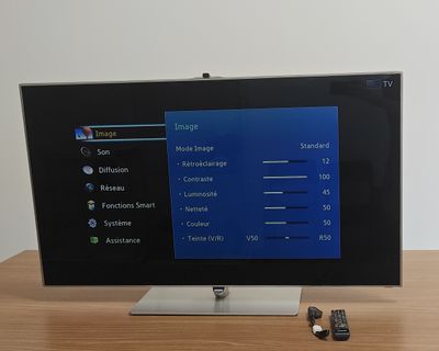 a flat screen tv sitting on a table with remote controls