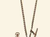 a gold chain with a pocket watch and a key on it