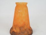a small orange glass vase sitting on a white surface