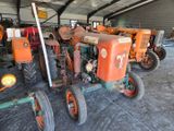 many old tractors parked in a garage together