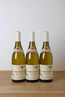 trois bouteilles de vin posées sur une table en bois à côté d'une bouteille de vin