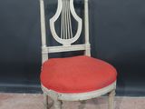 a white chair with a red cushion and a harp on the back