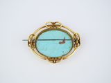 a close up of a gold and turquoise stone broochle