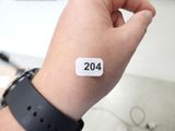a person holding a wrist that has a white sticker on it