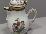 a tea pot with a cup and saucer on a table