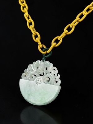 a white jade pendant with a yellow chain on a black background