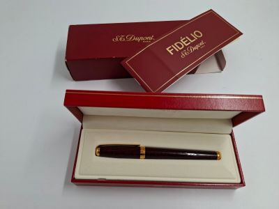 une boîte rouge contenant un stylo, posée sur une table