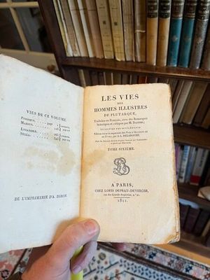 une personne tenant un livre à la main devant une bibliothèque