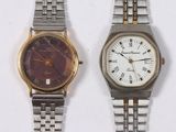 two watches sitting next to each other on a white surface