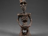 une statue en bois représentant un squelette tenant une tête humaine